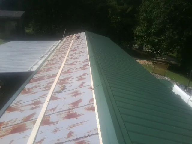 Old rusted panels beside newly installed green metal roofing — Wind Damage Roof Repair by Roofing Brothers in Lansdowne
