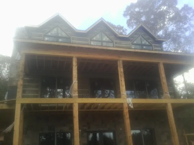 Dormers and porch framing on a large log home under construction — Roof Coating work by our crew in Lansdowne