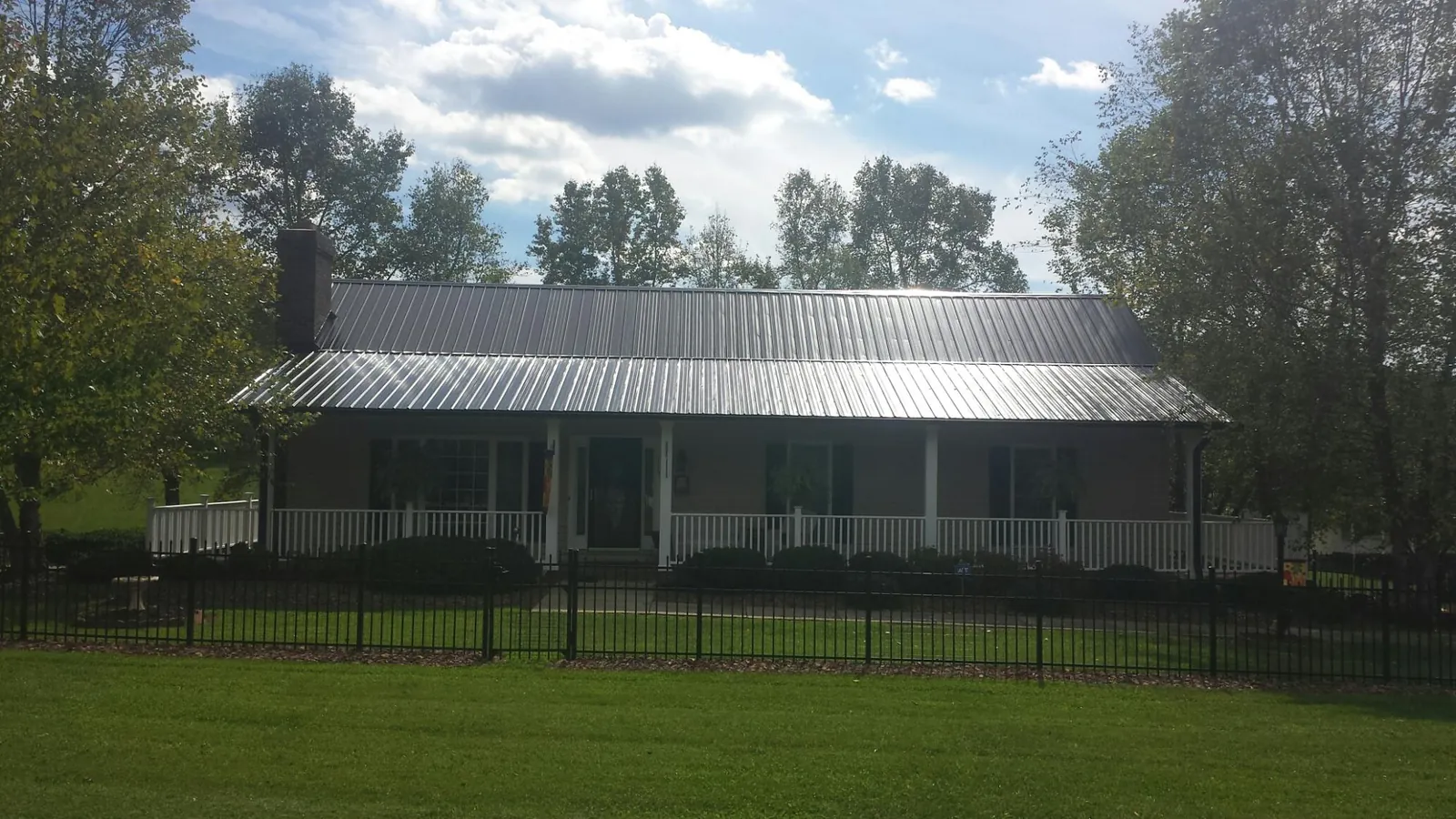 Gray metal roof on a brick ranch with a full width front porch — Gutter Guard Installation work by our crew in Lansdowne