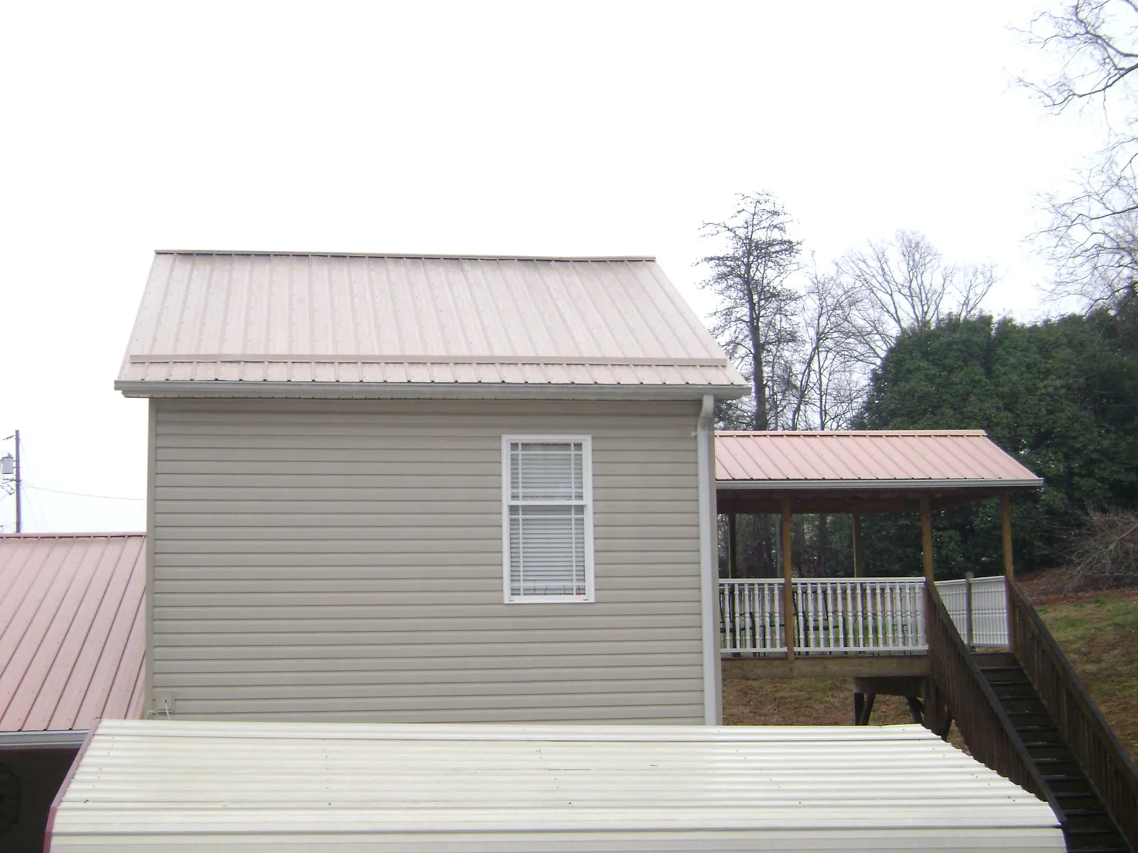 Tan metal roofs on a two story addition and attached porch, from a Roof Replacement job in Lansdowne
